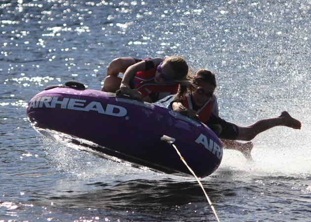 Capturing the fun when two sisters go tubing on Lake Sunapee at the end of a summer day by Echo Cove Photography