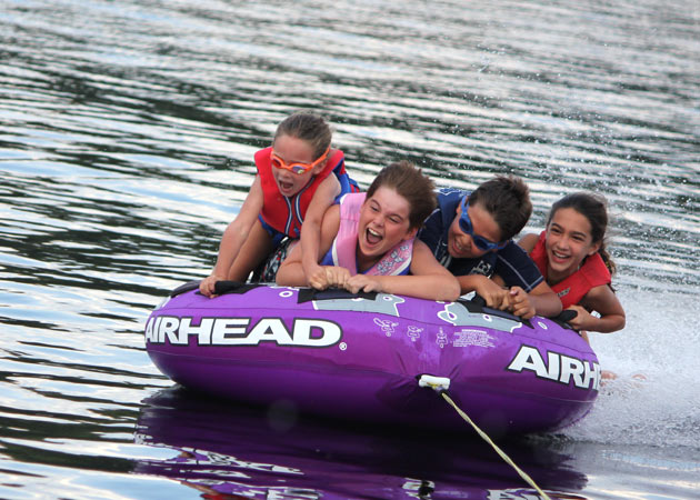 Capturing the fun of four kids tubing together on a beautiful summer day on Lake Sunapee by Echo Cove Photography